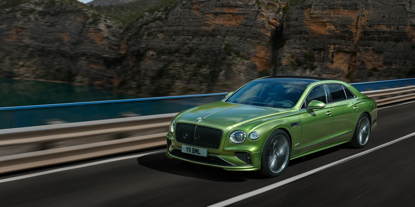 Bentley Marbella Bentley New Flying Spur Speed v8 hybrid sedan driving dynamically on a mountain road in Tourmaline Green paint