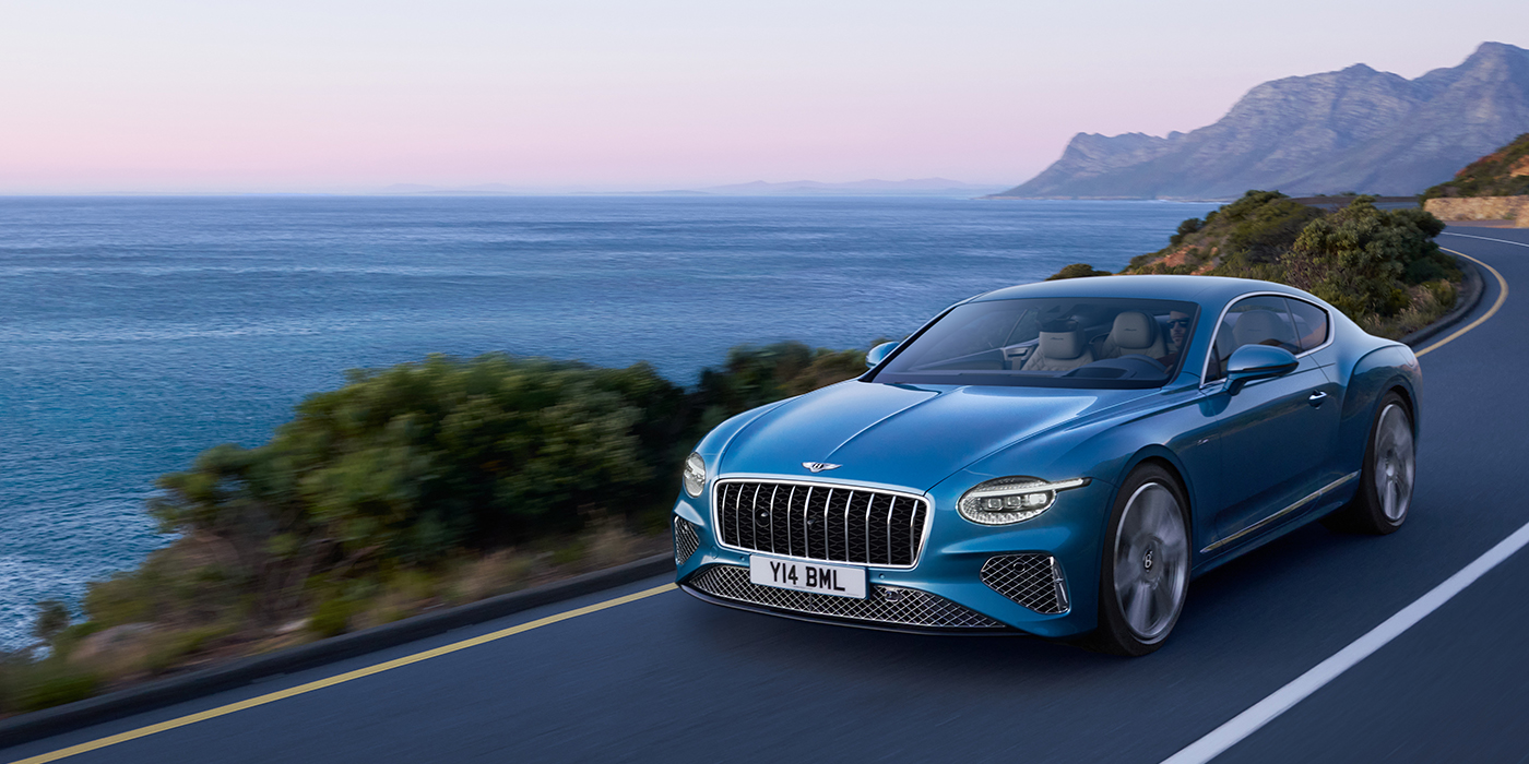 Bentley Marbella New Bentley Continental GT Azure coupe in Light Windsor blue paint with 22 inch Azure wheels and chrome grill, driving dynamically by the sea