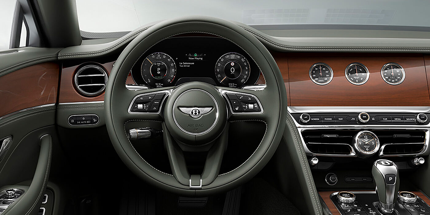 Bentley Marbella New Bentley Flying Spur sedan front cabin in Cumbrian Green hide and Crown Cut walnut veneer showing steering wheel and Rotating Display with three clocks on face