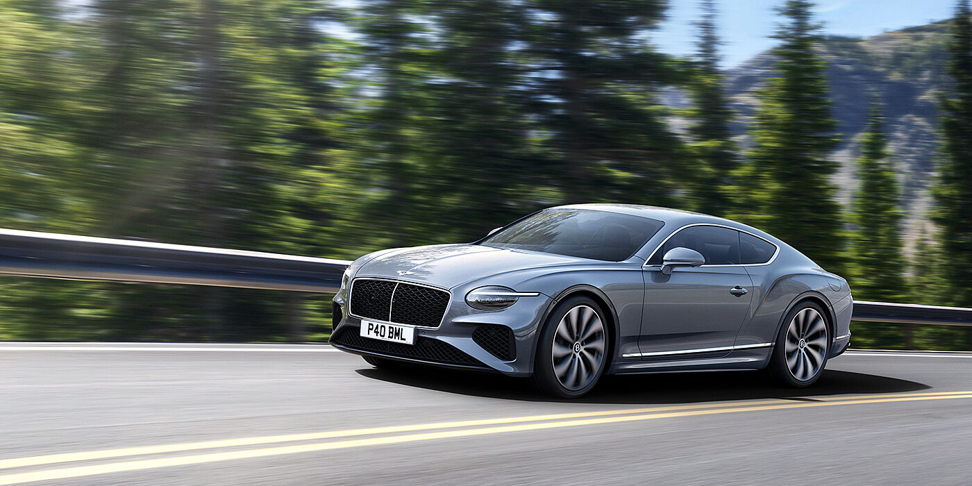 Bentley Marbella New Bentley Continental GT coupe in Silverlake paint and 22 inch ten-spoke wheels, driving dynamically on a tree-lined road in the sunshine