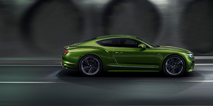  Bentley Marbella Bentley Continental GT coupe in Tourmaline Green paint driving in profile on a dark road