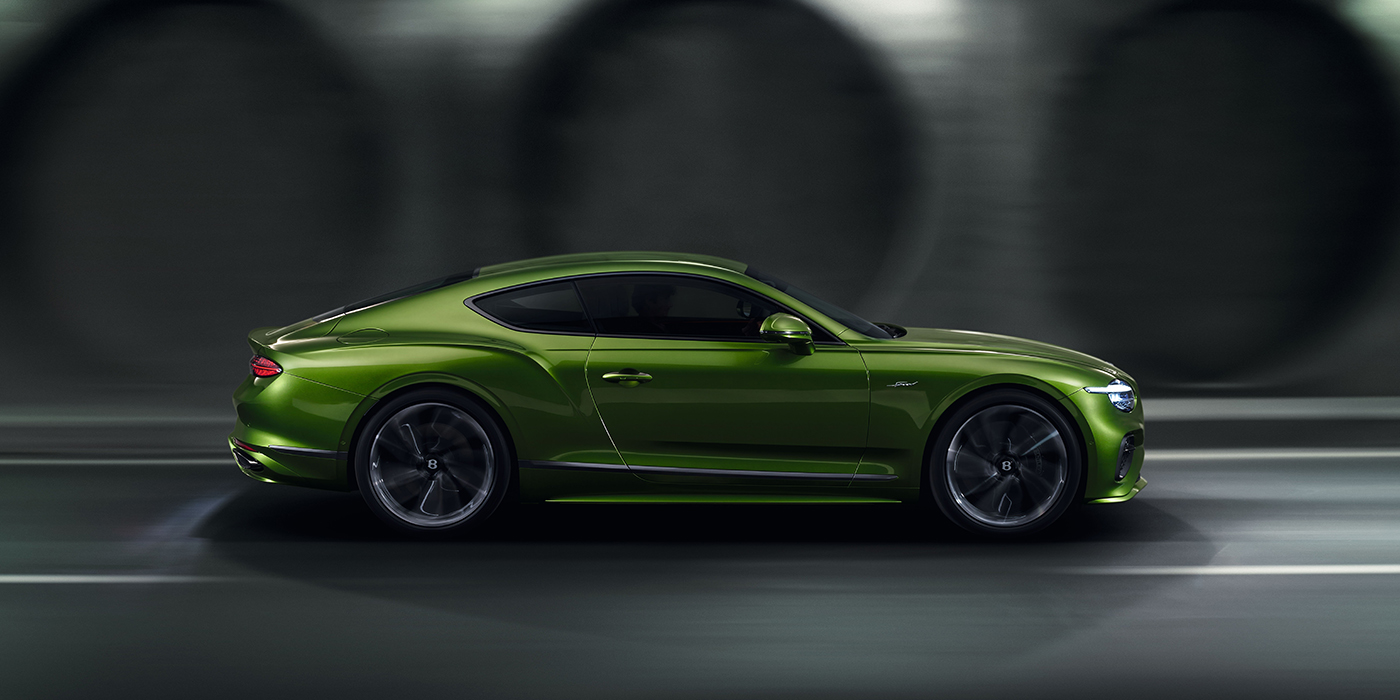 Bentley Marbella Bentley Continental GT coupe in Tourmaline Green paint driving in profile on a dark road