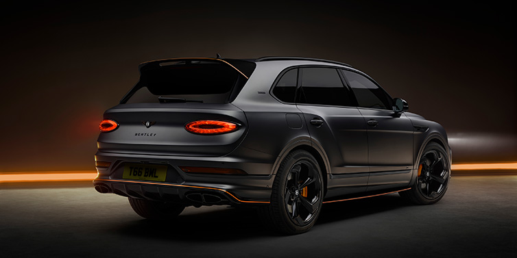 Bentley Marbella Bentley Bentayga S Black Edition SUV rear three quarter in Anthracite Satin paint against a dark red and yellow background