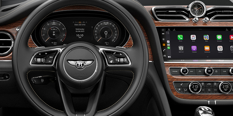 Bentley Marbella Bentley Bentayga SUV front interior detail of steering wheel and driver screens surrounded by Beluga black hide and Crown Cut Walnut veneer