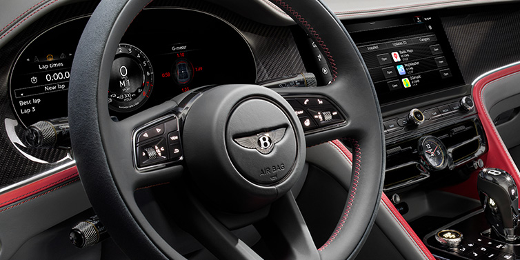 Bentley Marbella Bentley Flying Spur Speed sedan front interior detail showing steering wheel and driver screens surrounded with Hotspur red and Gravity Grey hides